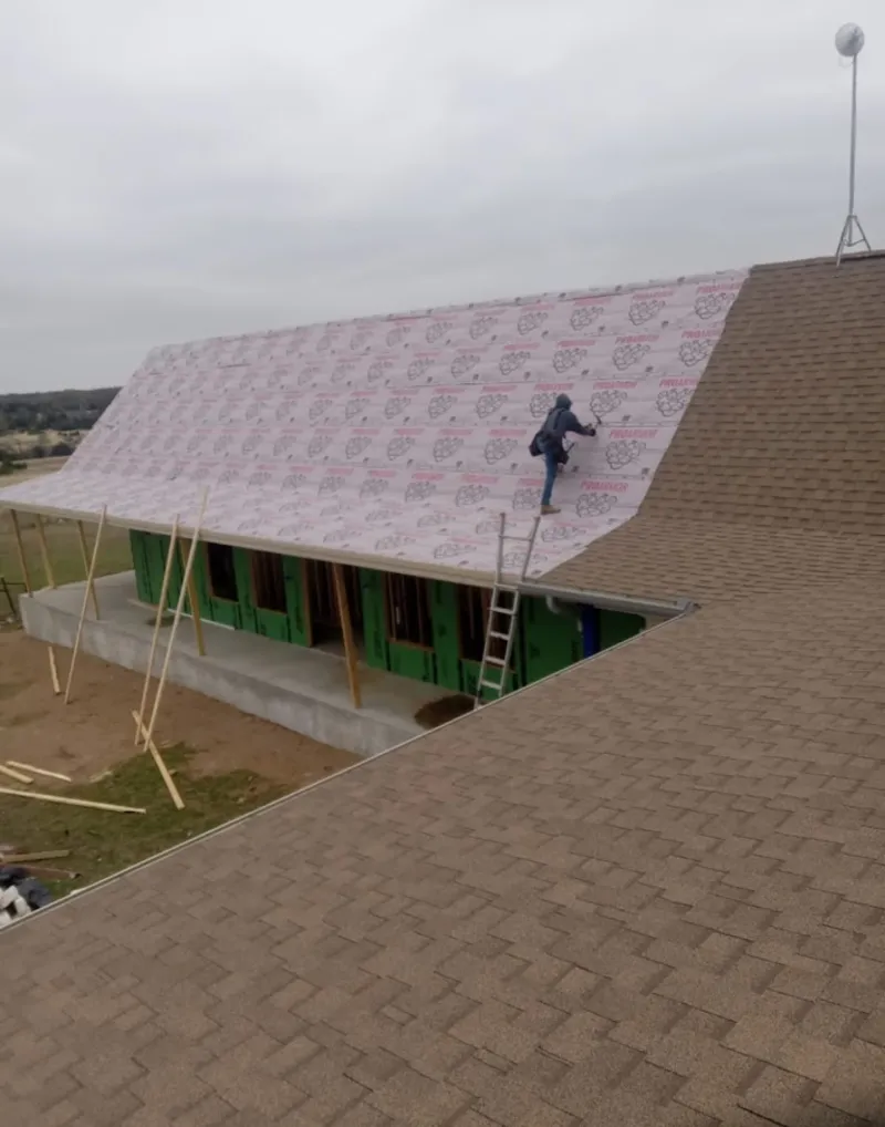 Worker preparing underlayment for a metal roof installation in East Hartford